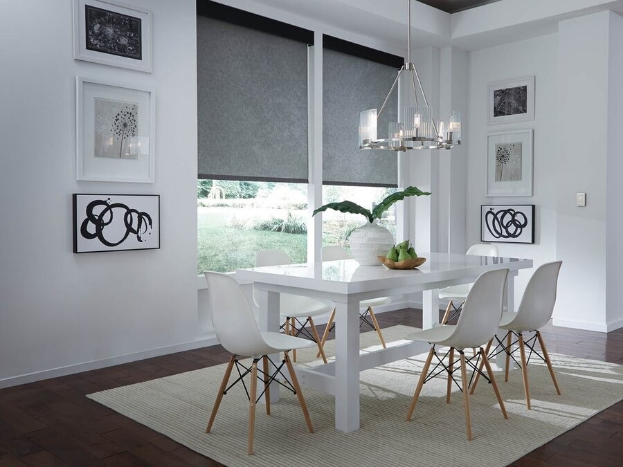 A residential dining space with a table and window featuring smart shades.